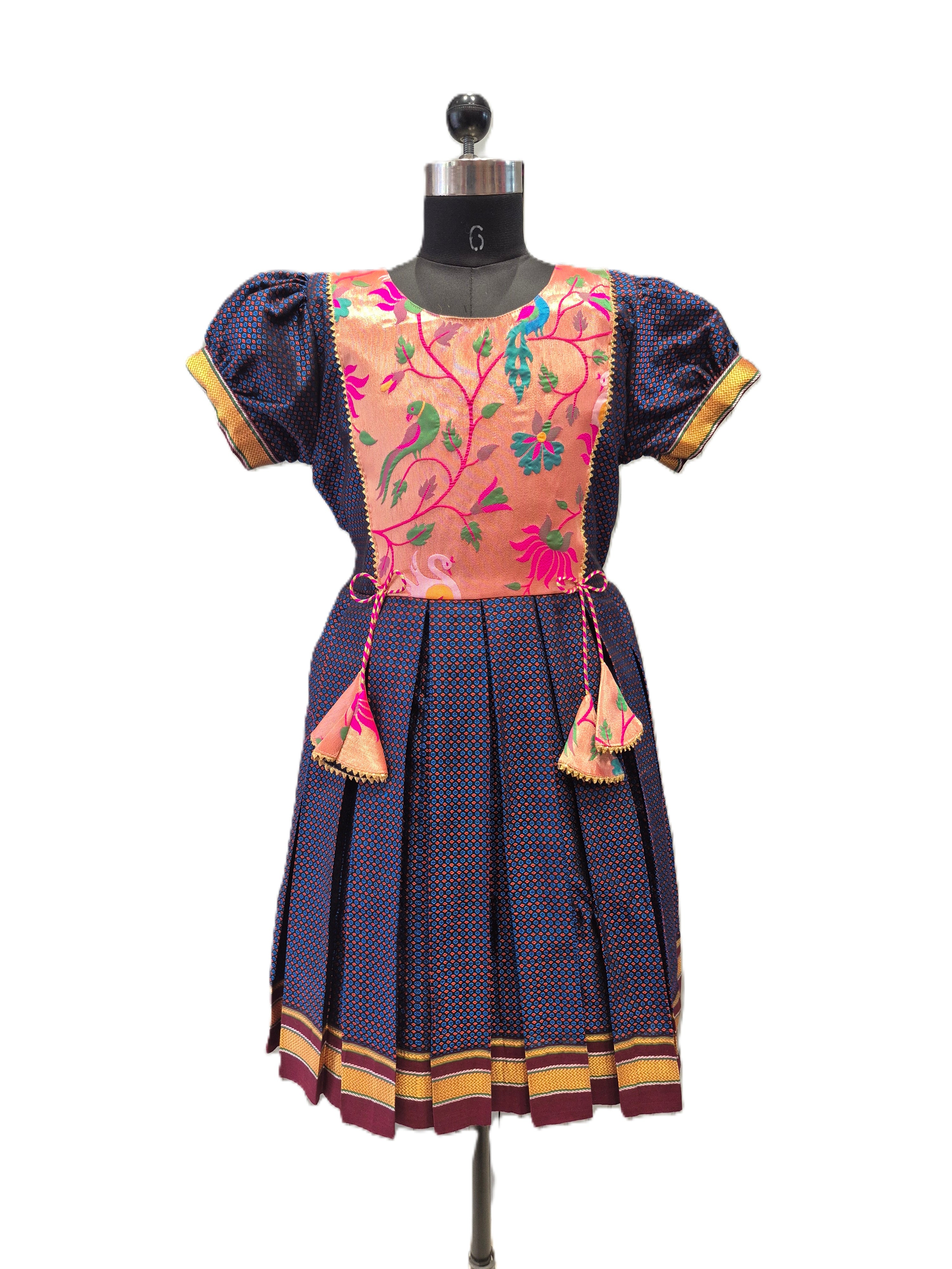 A traditional Indian salwar suit dress displayed on a black mannequin. The dress features a navy blue base with a fine red and yellow dotted pattern, a peach-colored embroidered yoke with a bird and floral motif, and gold and maroon borders. - House of Kritee