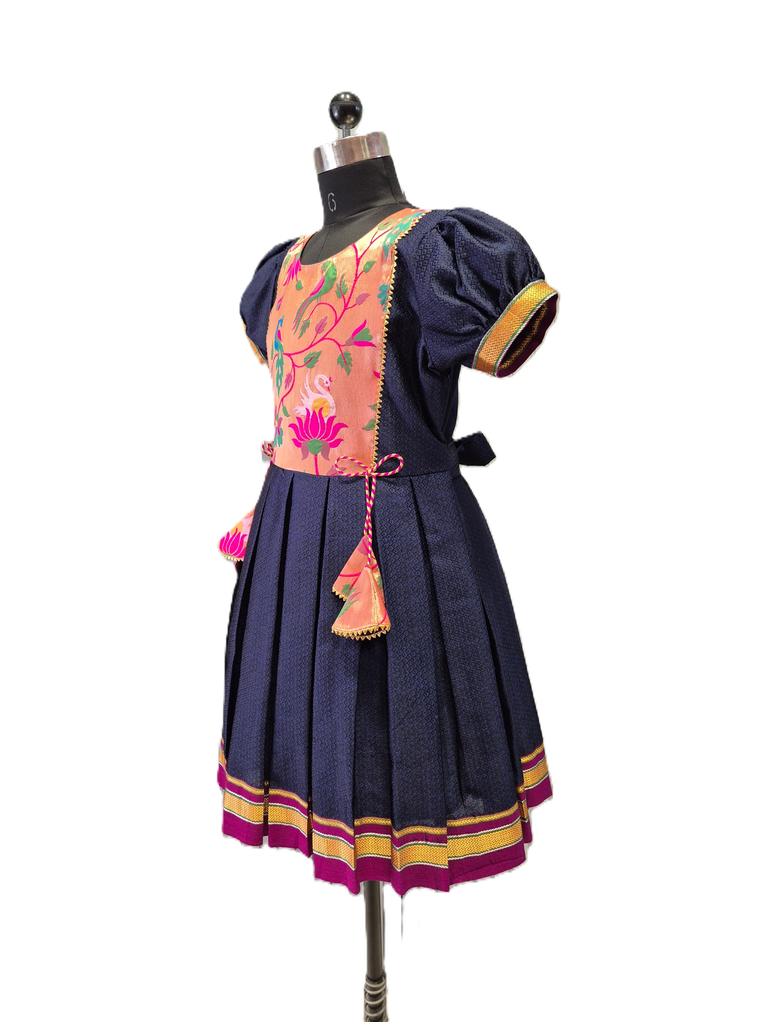 A traditional short-sleeve dress displayed on a mannequin against a white background. The dress features a navy blue skirt and sleeves, a peach-colored embroidered bodice with floral patterns, and gold and pink trim details. - House of Kritee