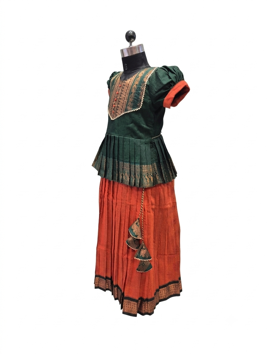 A traditional Indian outfit displayed on a black dress form mannequin against a plain white background. The outfit features a dark green short-sleeved top with gold embroidery and a pleated skirt in rust orange with a matching embroidered border. - House of Kritee