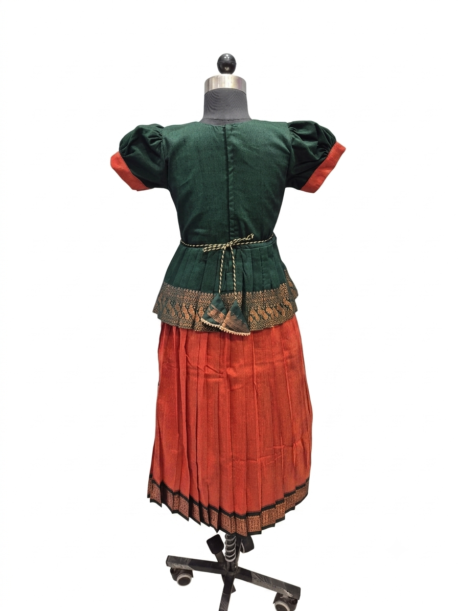 A traditional Andean-style dress displayed on a dress form mannequin, featuring a dark green velvet-like top with red sleeve cuffs, a gold patterned waistband, and a pleated rust-red skirt with a gold patterned hem - House of Kritee