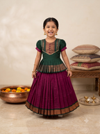 A Desi girl model smiling happily in a vibrant green and red Kalyani Gadhawal Parkar-polka traditional dress inside a soft cream room - House of Kritee
