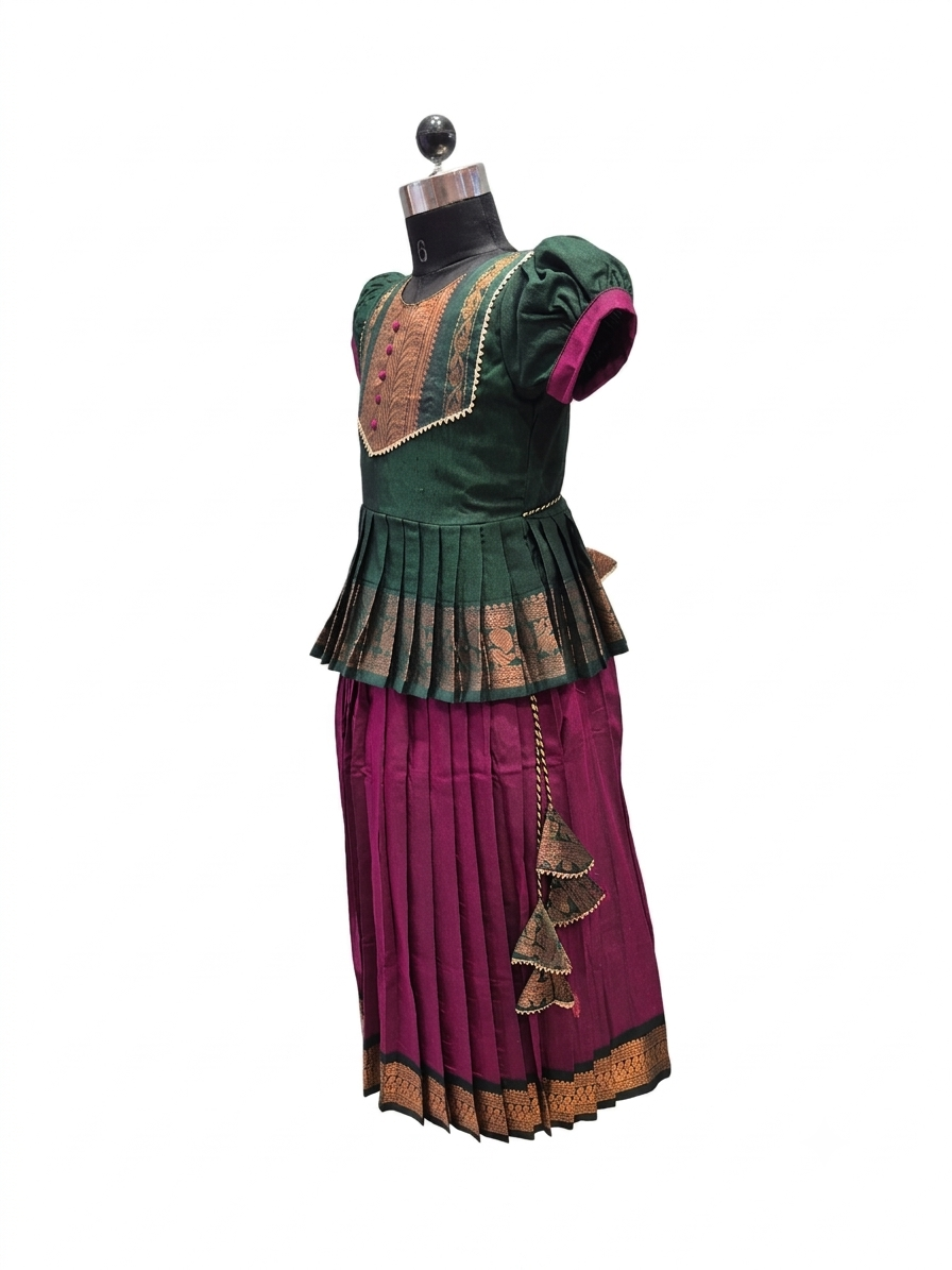 A traditional Indian ethnic outfit displayed on a black dress form mannequin against a plain white background. The outfit features a dark green embroidered blouse with gold patterns and magenta sleeves, paired with a matching pleated magenta skirt adorned with gold embroidery and a decorative hanging tassel. - House of Kritee