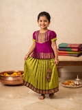 A Desi girl model smiling happily in a vibrant green and red Kalyani Gadhawal Parkar-polka traditional dress inside a soft cream room - House of Kritee