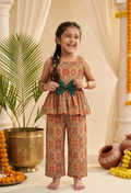 Happy Desi digital girl wearing a premium orange and brown geometric tile print cotton peplum top with a green waist bow and matching trousers in a soft cream garden background