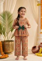Happy Desi digital girl wearing a premium orange and brown geometric tile print cotton peplum top with a green waist bow and matching trousers in a soft cream garden background