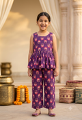 Happy Desi digital girl smiling in a premium purple cotton full co-ord set featuring a pink lotus floral print peplum top and matching trousers in a soft cream garden background.