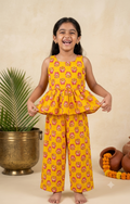 Happy Desi digital girl smiling in a premium mustard yellow cotton full co-ord set featuring a pink lotus floral print peplum top and matching trousers in a soft cream garden background