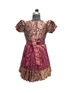 A short-sleeved dress displayed on a mannequin, featuring a rich magenta and gold brocade pattern with a matching waist tie and ruffled hem. - House of Kritee