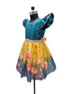 A toddler girl's dress displayed on a black mannequin torso against a plain white background. The dress has a teal blue velvet bodice with gold polka dots and short puff sleeves, a beige embroidered waistband, and a flared yellow-to-blue gradient skirt with a floral print. - House of Kritee
