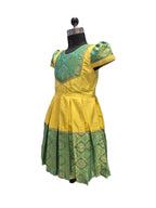 A yellow and green traditional dress displayed on a black dress form mannequin against a plain white background. - House of Kritee