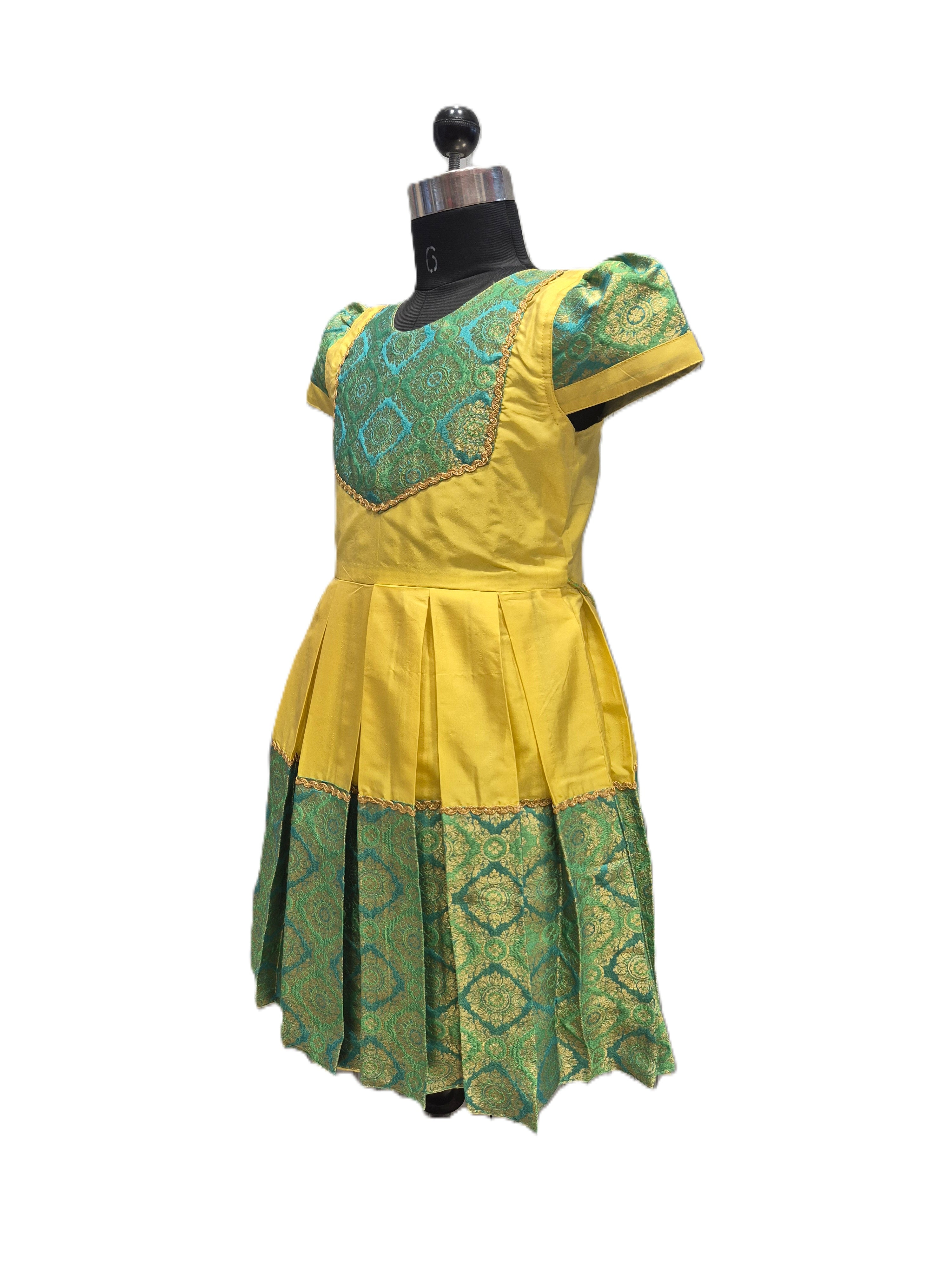 A yellow and green traditional dress displayed on a black dress form mannequin against a plain white background. - House of Kritee