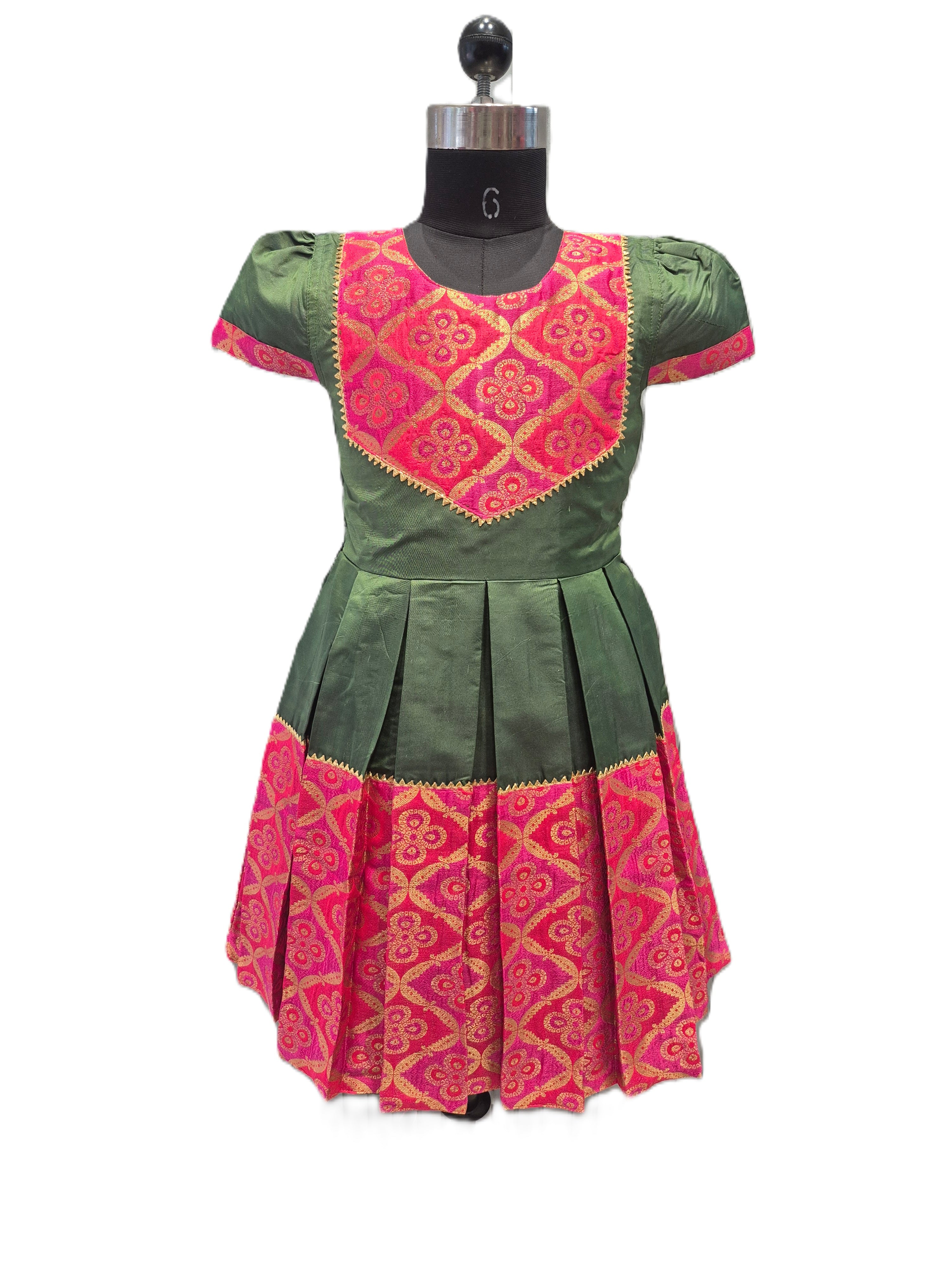 A green and pink traditional dress displayed on a black dress form mannequin against a plain white background. The dress features a green body with a bright pink embroidered yoke and a matching pink patterned hem. - House of Kritee