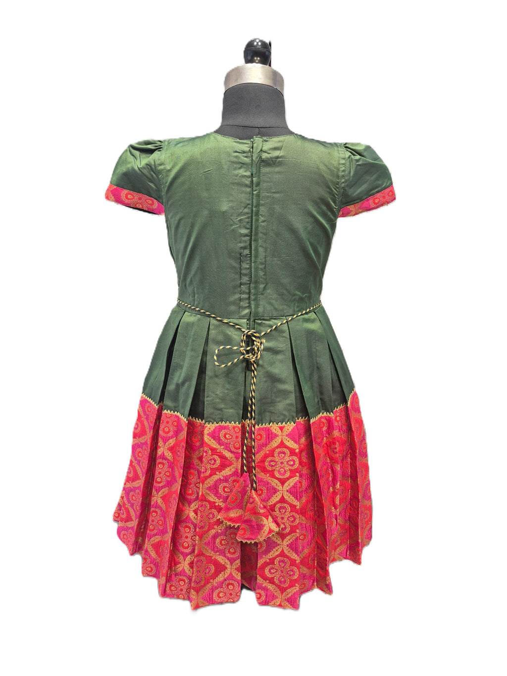 A green and pink traditional dress displayed on a mannequin from the back, featuring a green body with pink patterned trim, puffed short sleeves, and a gold chain tie at the waist. - House of Kritee