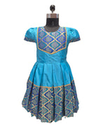 A blue short-sleeved dress displayed on a black dress form mannequin against a white background. The dress features a pleated skirt and a bodice with blue and gold geometric embroidery. - House of Kritee