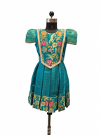 Happy Desi girl model wearing a teal blue silk knee length frock with floral jacquard bodice - House of Kritee