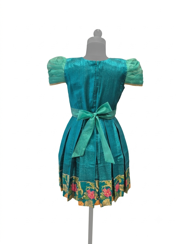 Happy Desi girl model wearing a teal blue silk knee length frock with floral jacquard bodice - House of Kritee