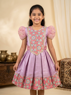 Happy Desi girl model wearing a soft lilac pink silk knee length frock with organza puff sleeves - House of Kritee