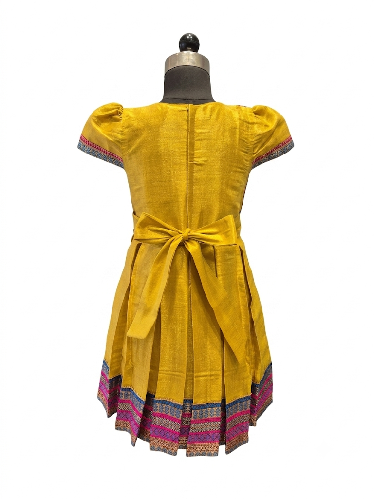 Happy Desi girl model wearing a yellow silk Angrakha knee length ethnic frock with geometric border - House of Kritee