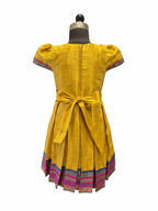 Happy Desi girl model wearing a yellow silk Angrakha knee length ethnic frock with geometric border - House of Kritee