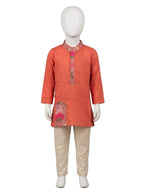 Young boy smiling in rust orange printed kurta and beige pajama set