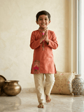 Young boy smiling in rust orange printed kurta and beige pajama set