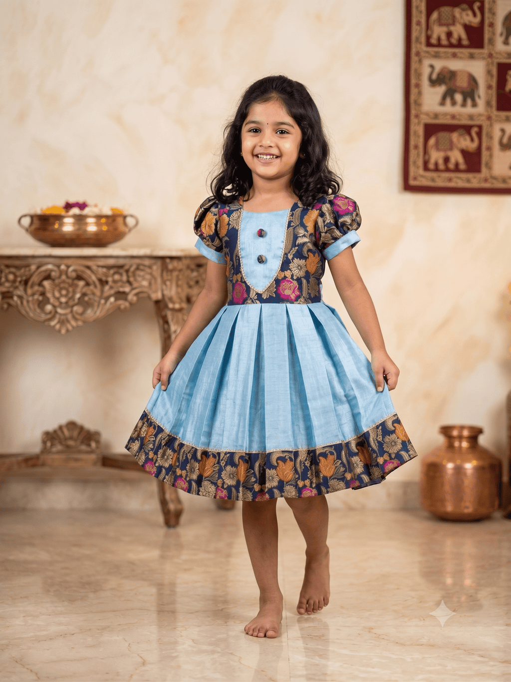 Happy young girl enjoying her premium sky blue and navy floral brocade silk knee-length ethnic frock in a warm cream room setup - House of Kritee