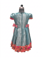 A short-sleeve teal blue dress displayed on a mannequin, featuring pink bow accents at the waist and a pink floral patterned hem. - House of Kritee