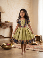 Happy young girl enjoying her premium navy blue and gold brocade silk knee-length ethnic frock in a warm cream living room setup - House of Kritee