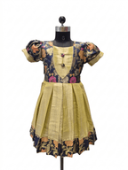 A traditional Indian salwar suit dress displayed on a black mannequin. The dress features a mustard yellow pleated skirt, a matching yellow embroidered yoke, and short puff sleeves with navy blue floral printed fabric. - house of Kritee