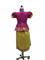A traditional Indian outfit displayed on a dress form mannequin, featuring a magenta purple short-sleeve top with yellow-green cuffs and a gold-trimmed peplum waist, paired with a pleated olive green skirt with a gold border. - House of Kritee