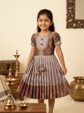 Girl model wearing ethnic jacket style silk frock with traditional golden zari border and tassels