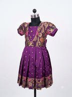 Young Indian girl smiling in a royal purple ethnic silk frock with floral brocade and gold zari details