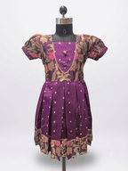 Young Indian girl smiling in a royal purple ethnic silk frock with floral brocade and gold zari details