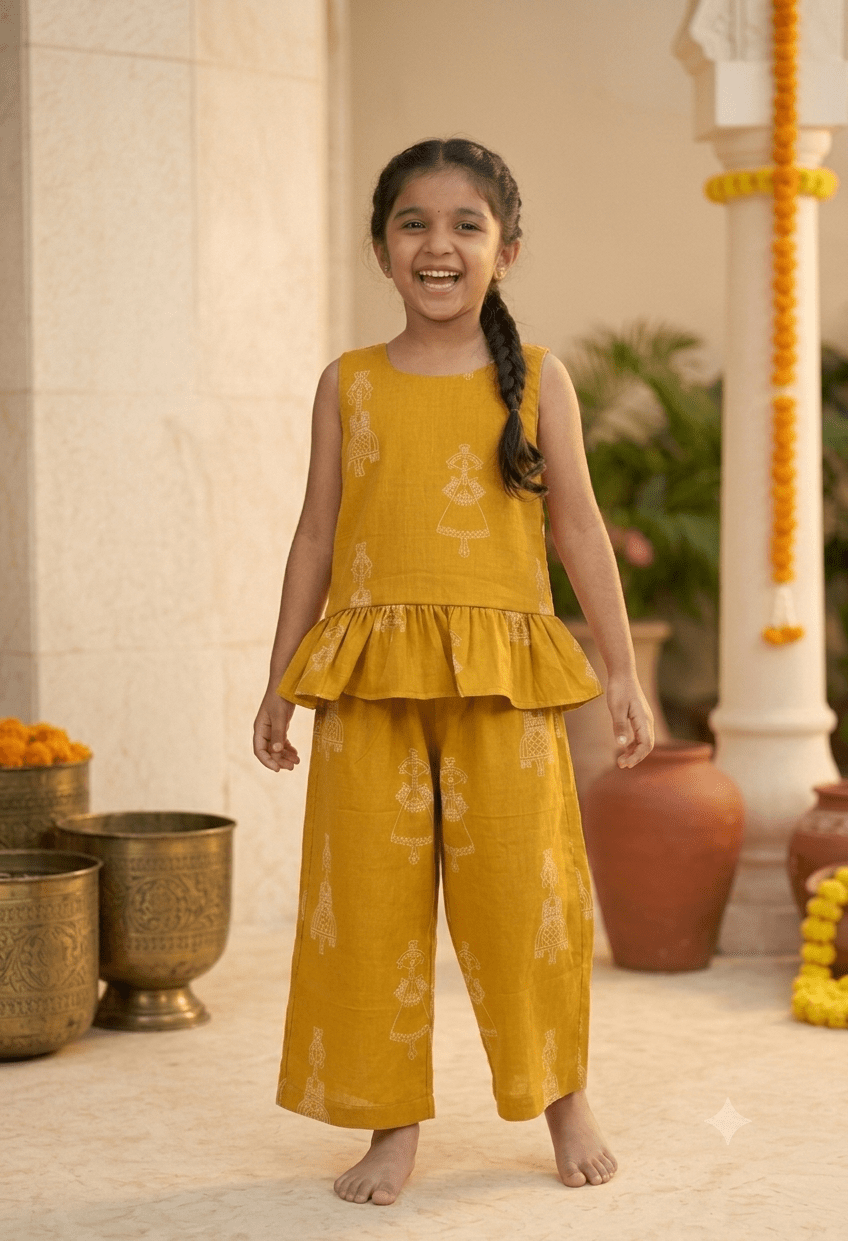Happy Desi digital girl enjoying in a premium mustard yellow cotton co-ord set with white traditional puppet print peplum top and trousers in a soft cream blurred garden setting