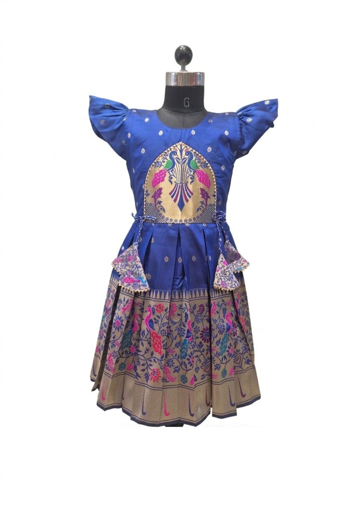 A royal blue traditional Indian dress displayed on a mannequin. The dress features a blue satin top with cap sleeves, a central gold and multicolor embroidered motif, and a tiered skirt decorated with pink, green, and blue floral patterns on a beige base.