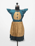 Young Desi girl smiling in a traditional peacock teal and gold ethnic silk frock with flutter sleeves