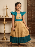Young Desi girl smiling in a traditional peacock teal and gold ethnic silk frock with flutter sleeves