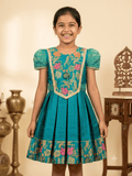 Happy Desi girl model wearing a teal blue silk knee length frock with floral jacquard bodice - House of Kritee