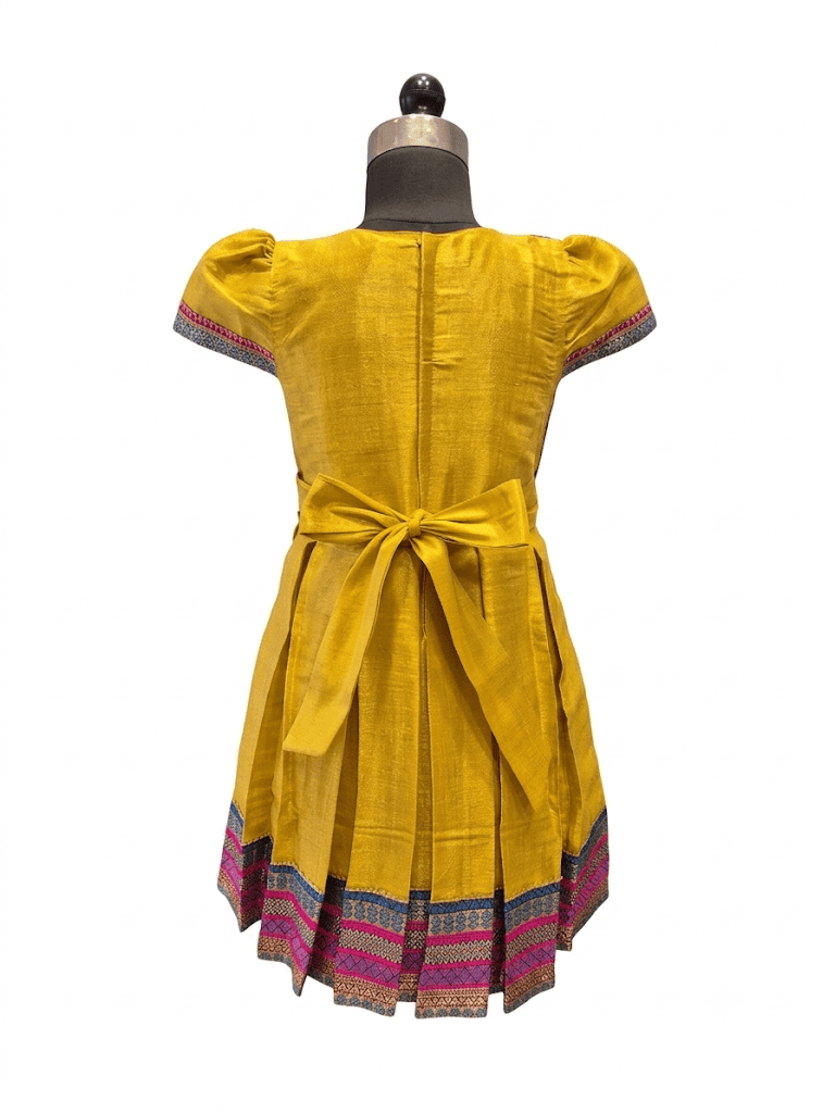 Happy Desi girl model wearing a yellow silk Angrakha knee length ethnic frock with geometric border - House of Kritee