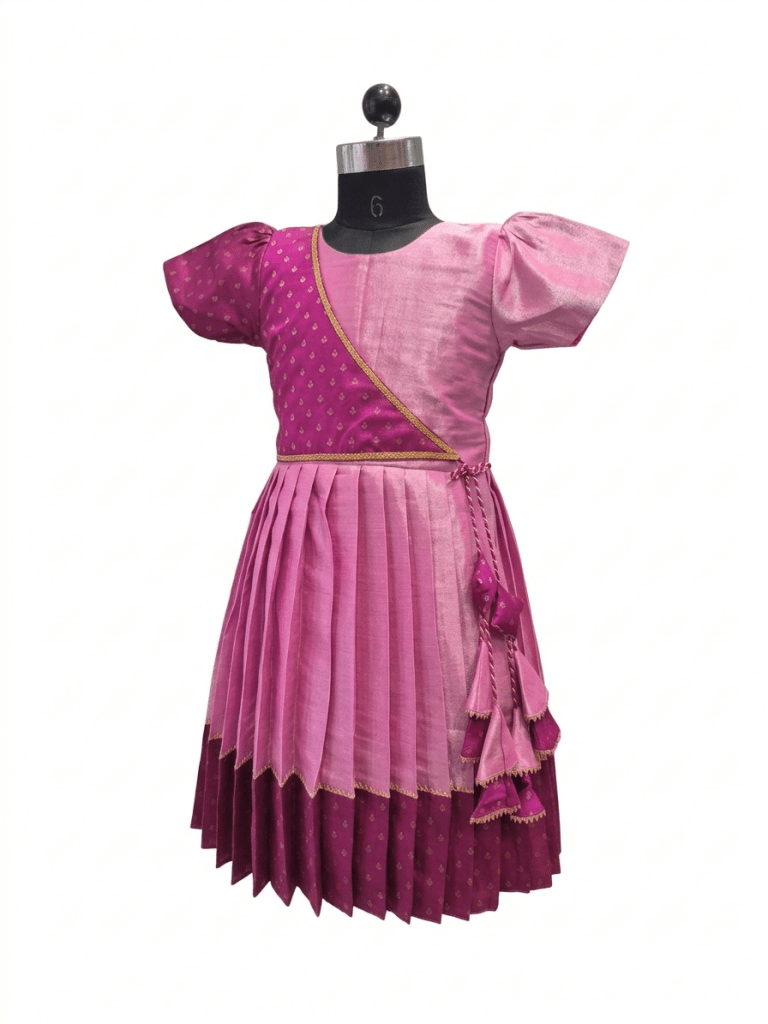 "Happy young Indian girl model smiling in a premium dual-shade pink and magenta silk ethnic knee-length frock with gold borders and tassels"