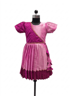 "Happy young Indian girl model smiling in a premium dual-shade pink and magenta silk ethnic knee-length frock with gold borders and tassels"