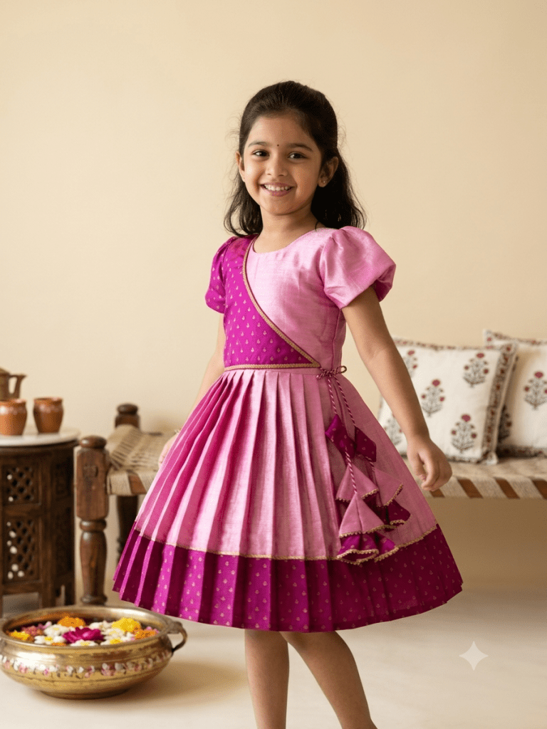 "Happy young Indian girl model smiling in a premium dual-shade pink and magenta silk ethnic knee-length frock with gold borders and tassels"