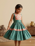 A beautiful teal-green silk tiered frock for girls, with a richly embroidered yoke and hem border