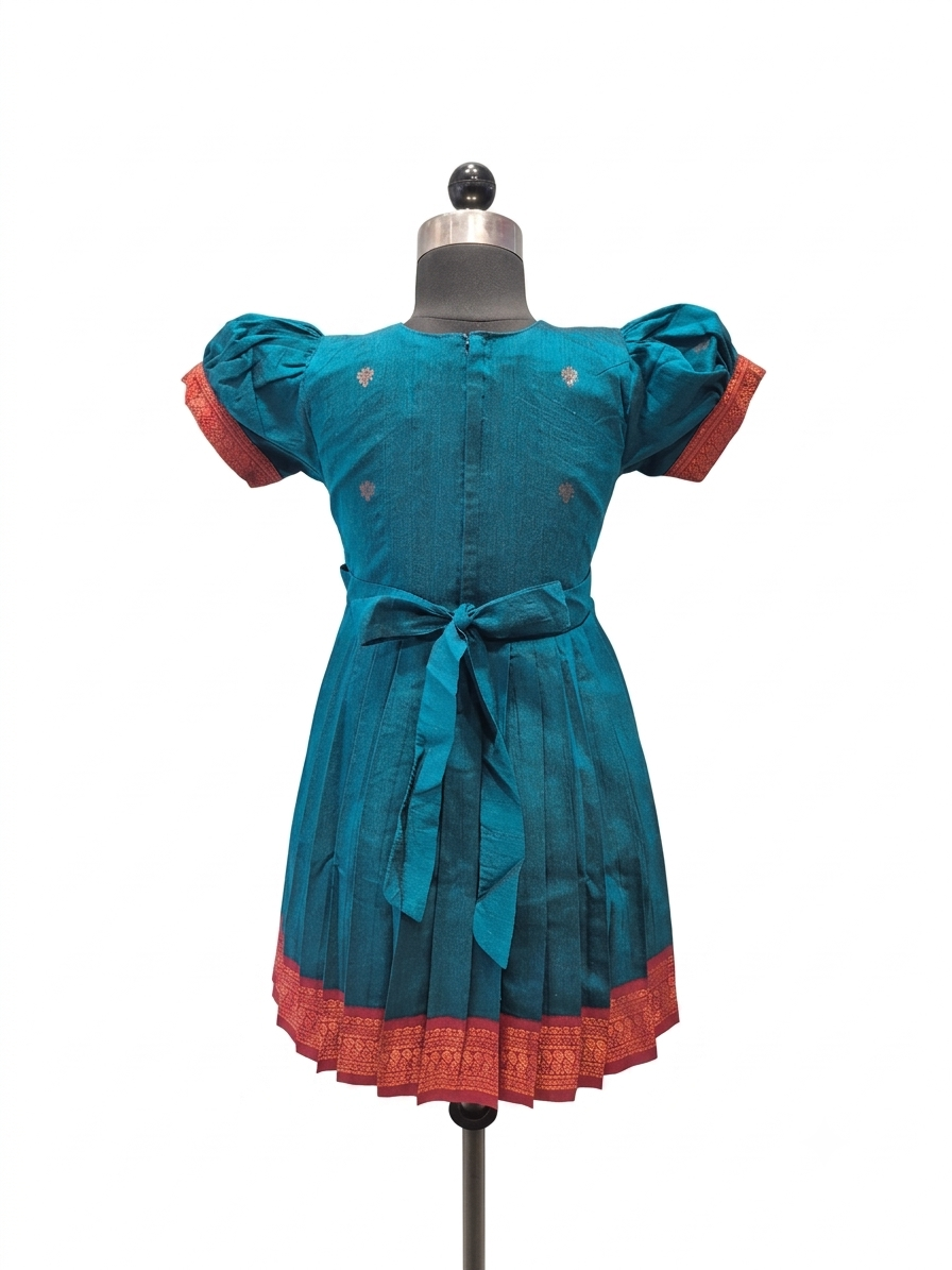 A teal blue cotton dress displayed on a mannequin, featuring puff sleeves with red cuffs, a matching waist tie, and a red patterned hem.