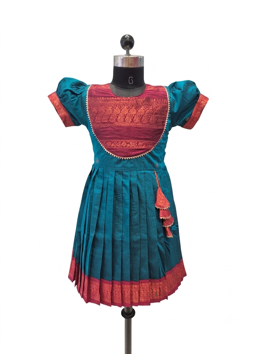 A traditional Indian girl's dress displayed on a mannequin, featuring a teal blue body with a contrasting magenta-pink embroidered yoke and border details.