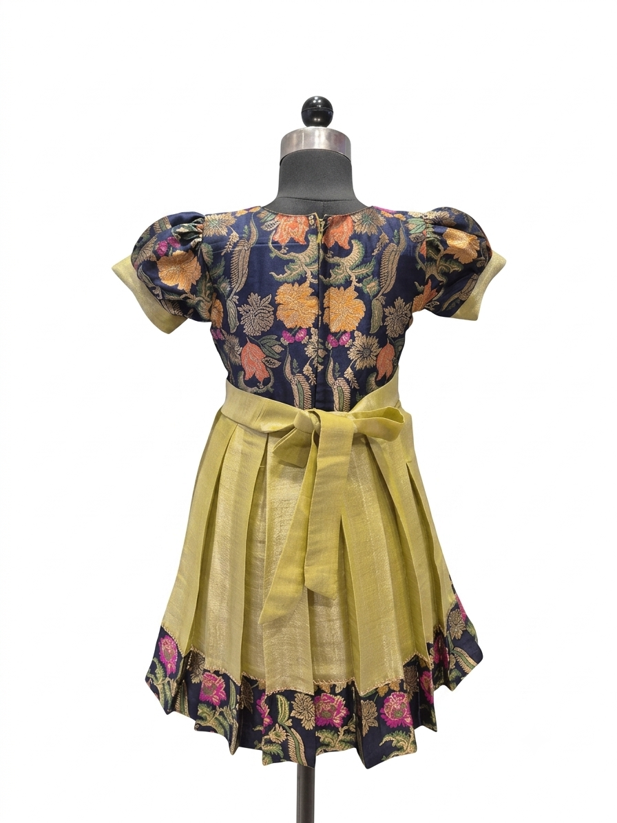 A short-sleeved dress displayed on a mannequin against a plain white background. The dress features a navy blue floral bodice with orange, pink, and green floral motifs, paired with a mustard yellow skirt and matching waist tie - house of Kritee