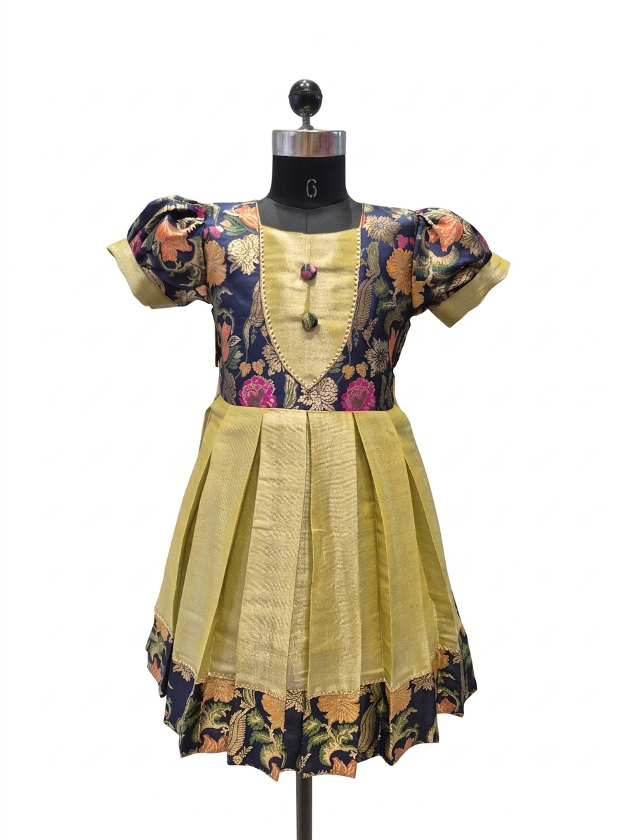 A traditional Indian salwar suit dress displayed on a black mannequin. The dress features a mustard yellow pleated skirt, a matching yellow embroidered yoke, and short puff sleeves with navy blue floral printed fabric. - house of Kritee