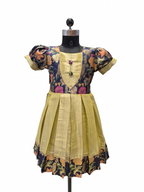 A traditional Indian salwar suit dress displayed on a black mannequin. The dress features a mustard yellow pleated skirt, a matching yellow embroidered yoke, and short puff sleeves with navy blue floral printed fabric. - house of Kritee