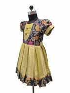 A short-sleeved traditional dress displayed on a black dress form mannequin against a white background. The dress features a dark navy blue floral printed bodice with yellow, pink, and orange floral motifs, and a pleated golden-yellow skirt with a matching floral border - house of Kritee