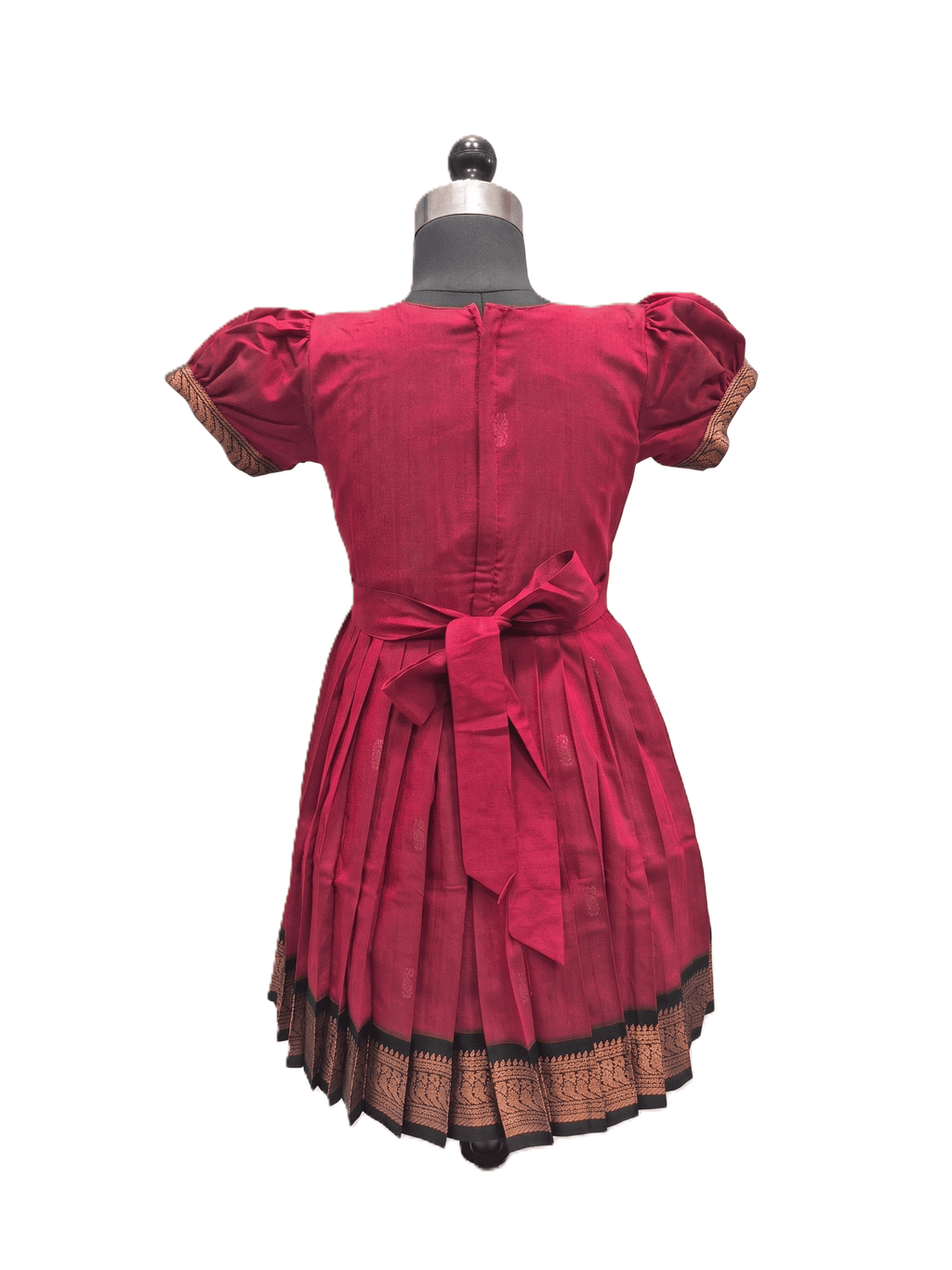 A red cotton dress with puff sleeves and a matching waist tie, displayed on a mannequin from the back. The dress features a pleated skirt and a decorative gold and black patterned border along the hem. - House of Kritee